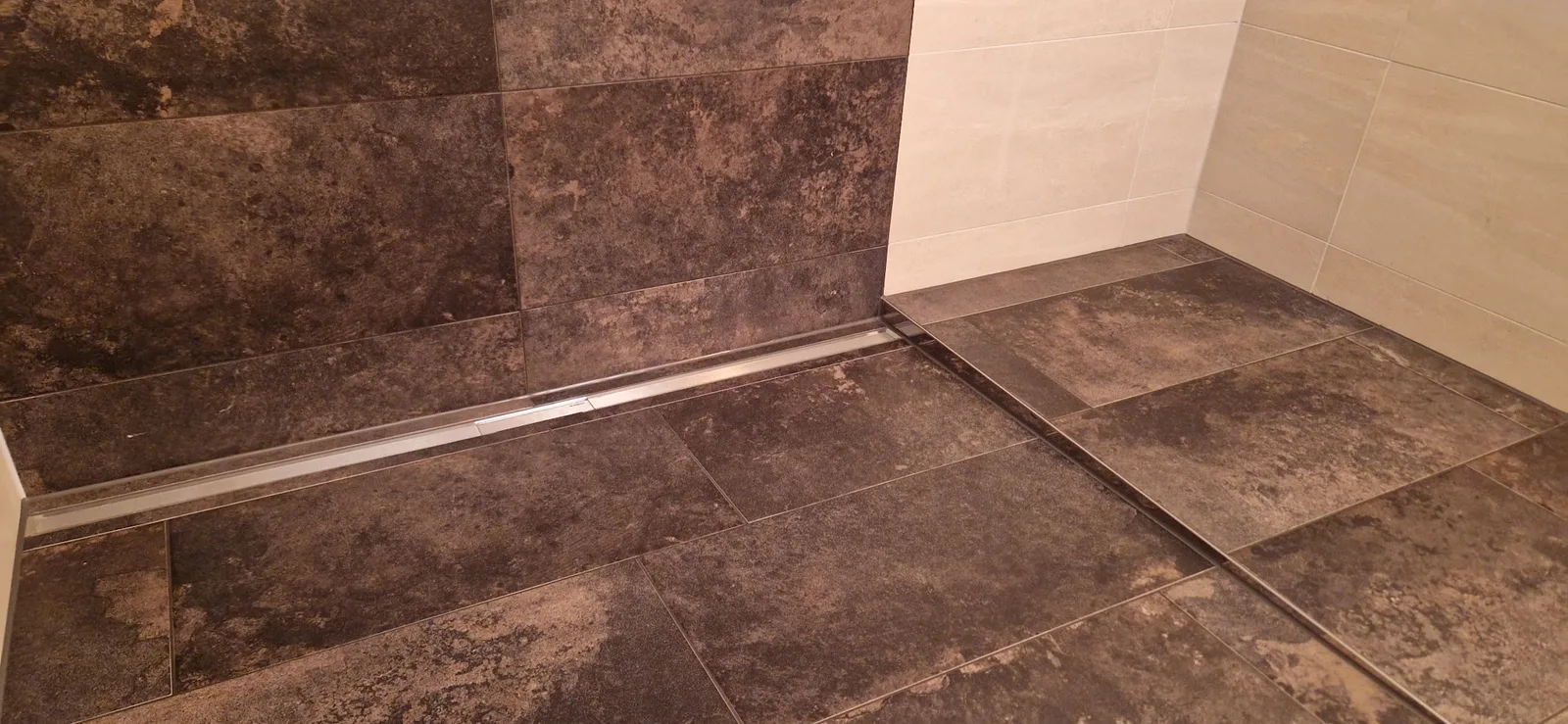 Bodengleiche Dusche mit dunklen Fliesen in Steinoptik und Duschrinne
